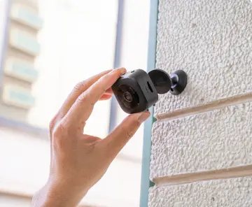 Hand adjusting a wall-mounted GuardHouse camera